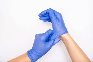 Nitrile disposable gloves being put on hand