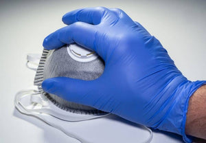 disposable gloved hand holding FFP2 valved respirator